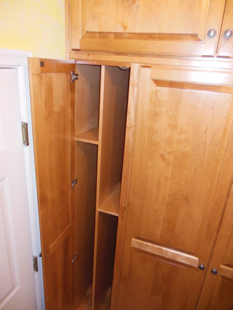 Laundry room cabinet with custom dividers for brooms, ironing board or trays.
